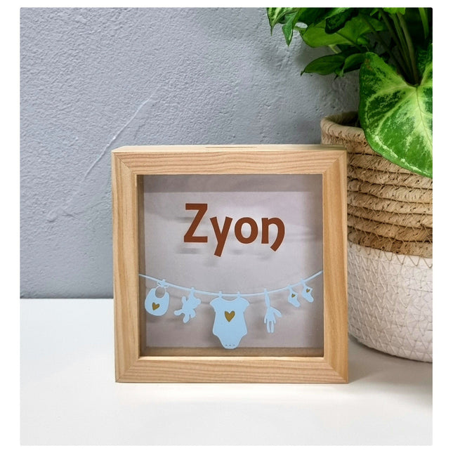 Een spaarpot met naam en waslijn met baby items eraan. Een leuk cadeau met naam!