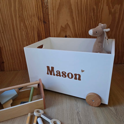 Witte speelgoedkist op wielen met de naam van het kindje er op in licht bruin