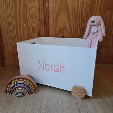 Witte speelgoedkist op wielen met de naam van het kindje er op in pastel roze